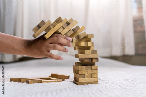 Young man pulling out wood block fail on building tower at home and drape change, choice business risking dangerous project plan failure construction