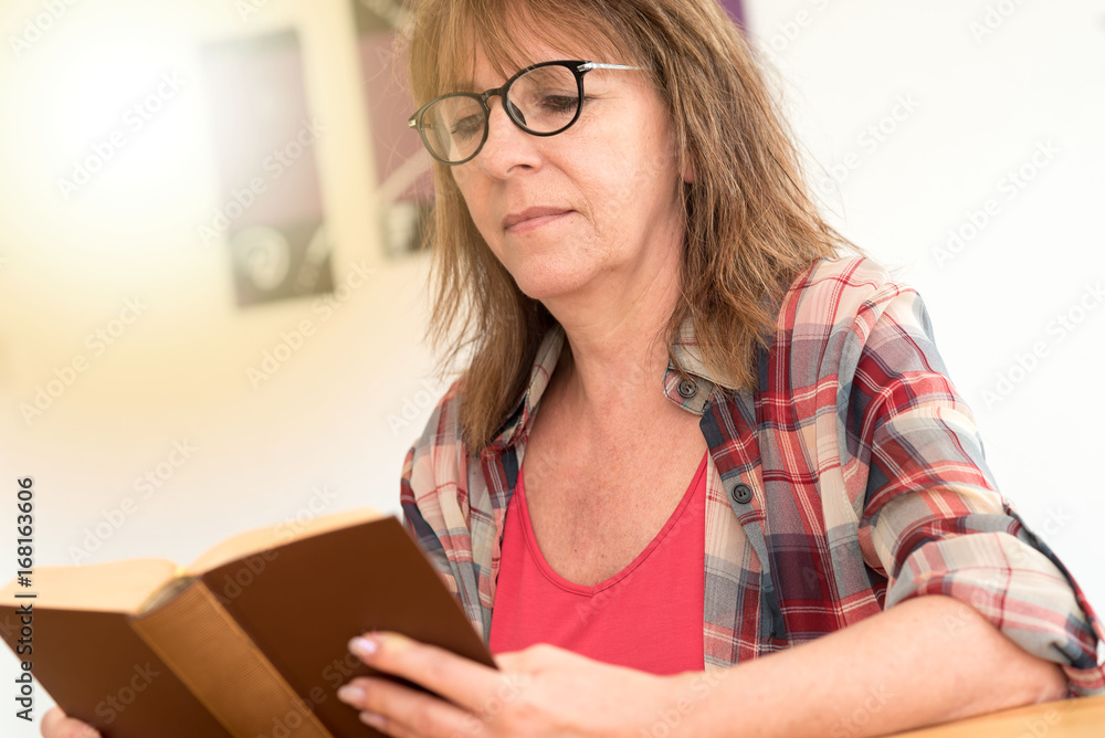 Mature woman reading a book, light effect Mature woman reading a book, light effect