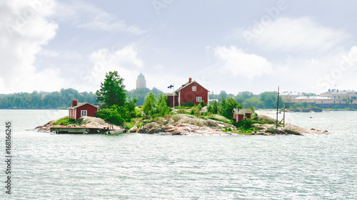 A small island with a house with the Helsinki skyline visible in the background. Taken near Suomenlinna, Finland