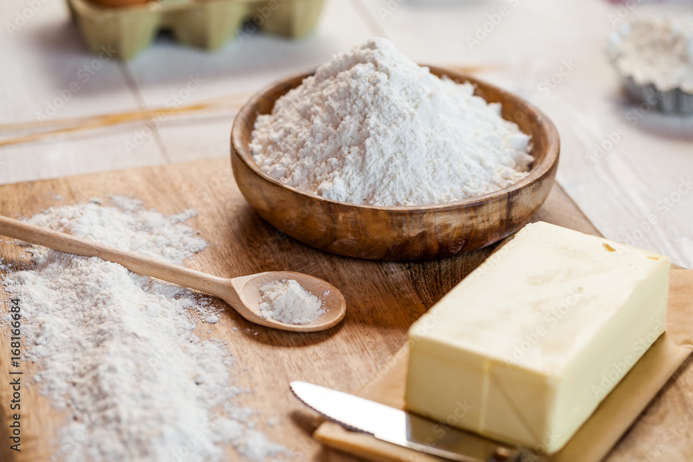 Baking ingredients in rural kitchen - dough recipe ingredients (eggs, flour, milk, butter, sugar) and rolling pin on wooden white table. Close up Baking ingredients in rural kitchen - dough recipe ingredients (eggs, flour, milk, butter, sugar) and rolling pin on wooden white table. Close up