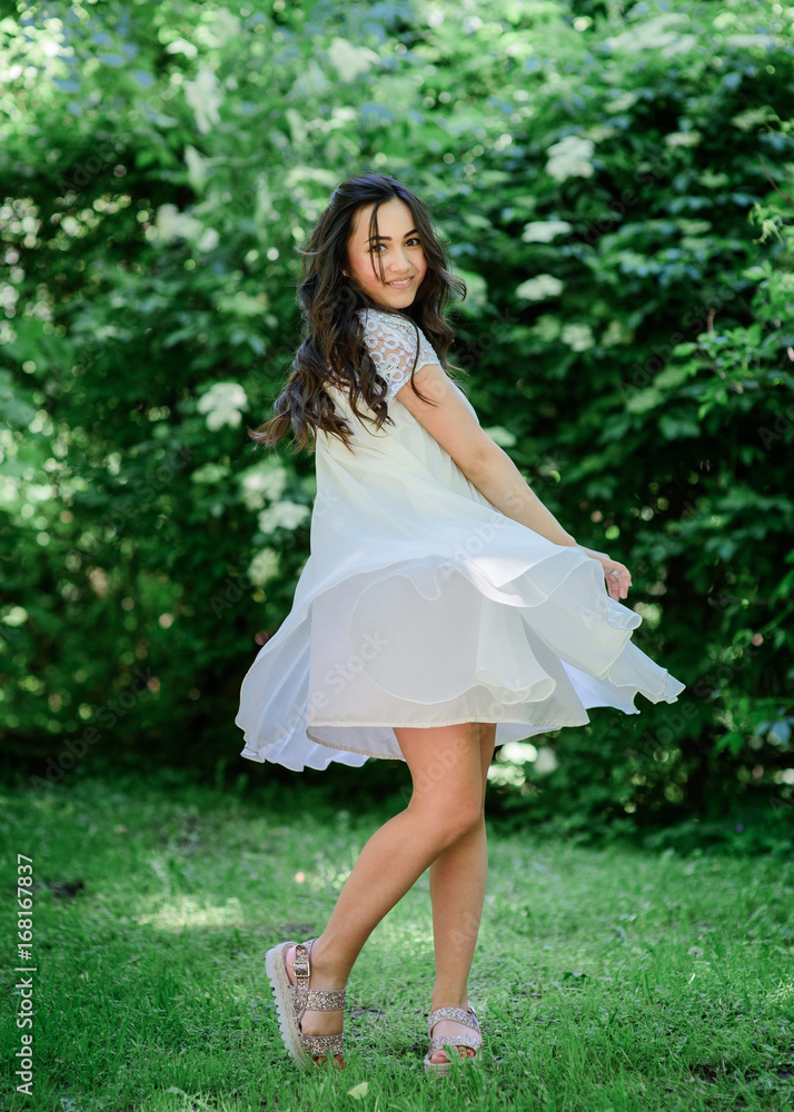 Smiling brunette woman in white dress poses in the garden Smiling brunette woman in white dress poses in the garden