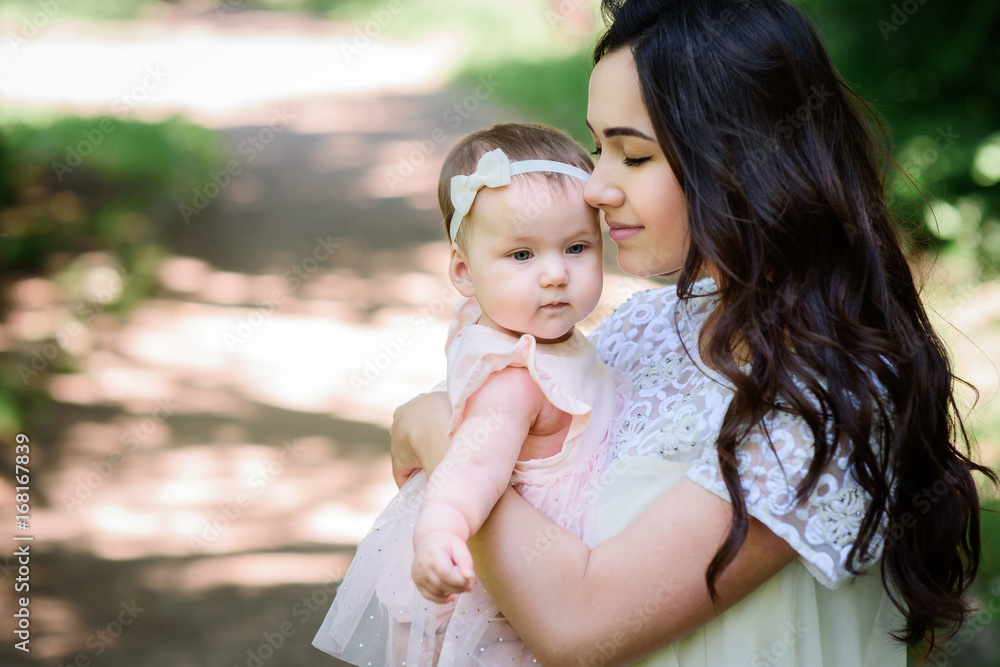 Dreamy young mommy holds her little daughter posing outside Dreamy young mommy holds her little daughter posing outside