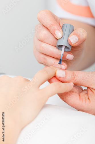 Manicurist applying nail polish on woman nails