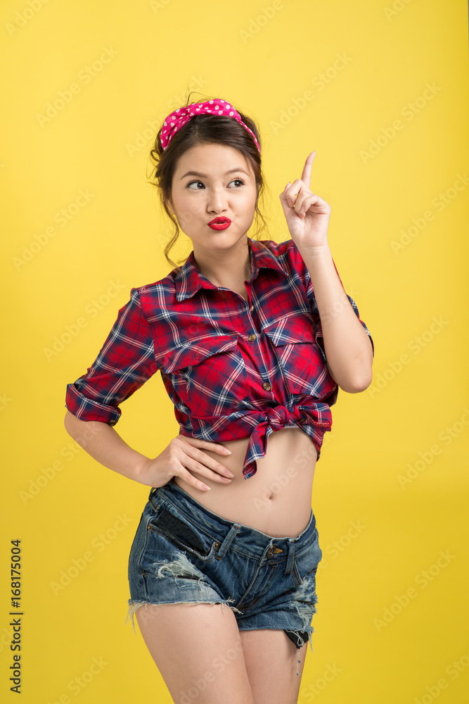 Asian woman retro portrait with pin-up make-up and hairstyle posing over yellow background. Asian woman retro portrait with pin-up make-up and hairstyle posing over yellow background.