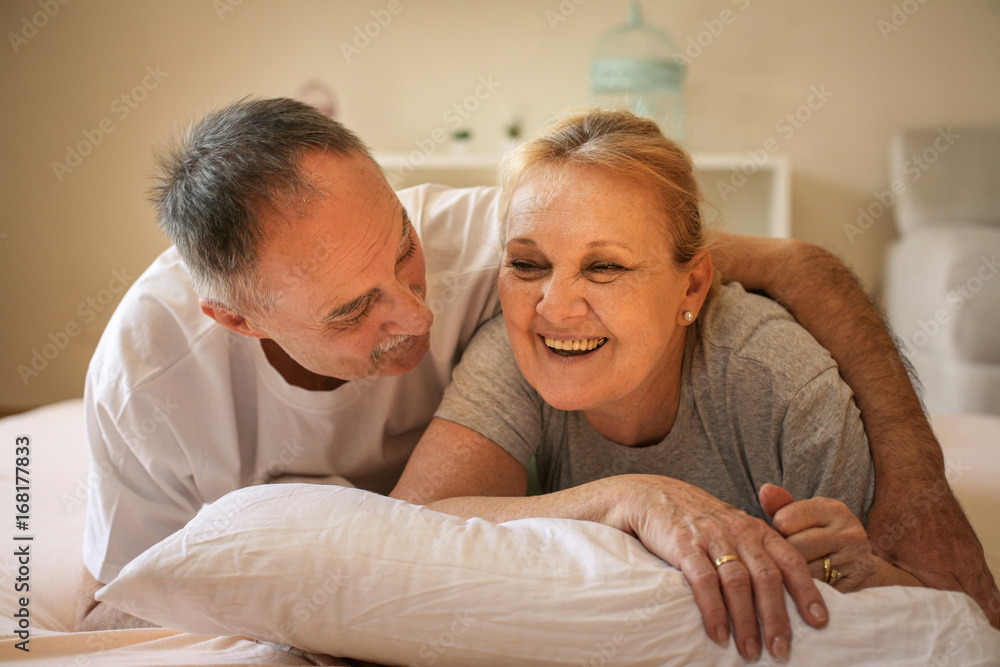 Senior couple lying on bed and having funny conversation. Senor man hugging senior woman. Senior couple lying on bed and having funny conversation. Senor man hugging senior woman.