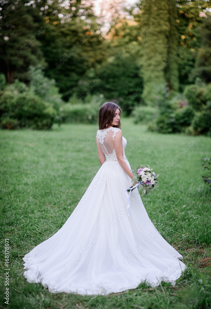 Pretty bride in a white dress stands in the garden