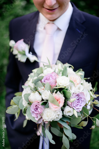 Groom holds tender wedding bouquet of roses