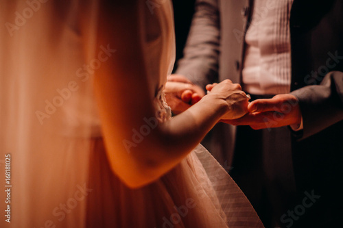 Groom holds tender bride s hands in his arms