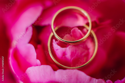 Golden rings lie on pink peonies