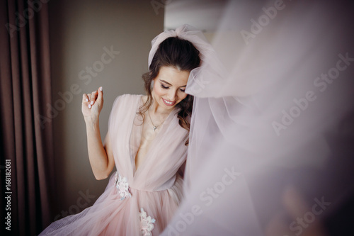 Beautiful bride in an ivory dress poses in a hotel room