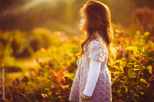 Little girl with red hair stand stands on the field