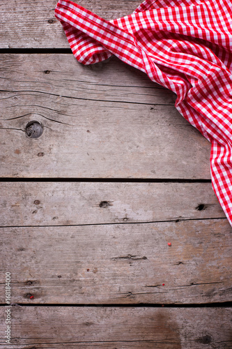 Red and white kitchen towel on rustic wooden background.