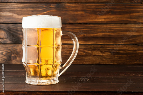 glass of cold frothy lager beer on old wooden table