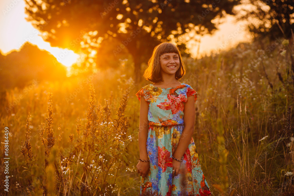 Obraz premium Pretty girl in a bright dress poses on the field