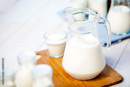 milk and glasses of milk on a wooden rustic table.