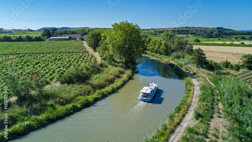 Aerial top view of boat in Canal du Midi from above, family travel by barge and vacation in Southern France 