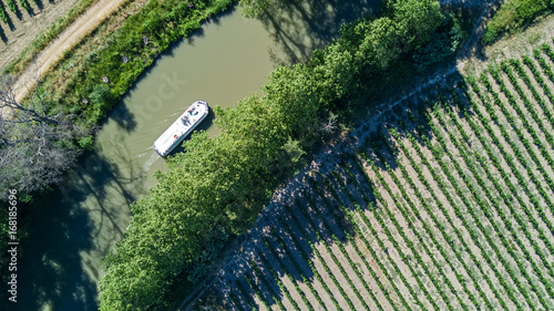 Aerial top view of boat in Canal du Midi from above, family travel by barge and vacation in Southern France
 photo