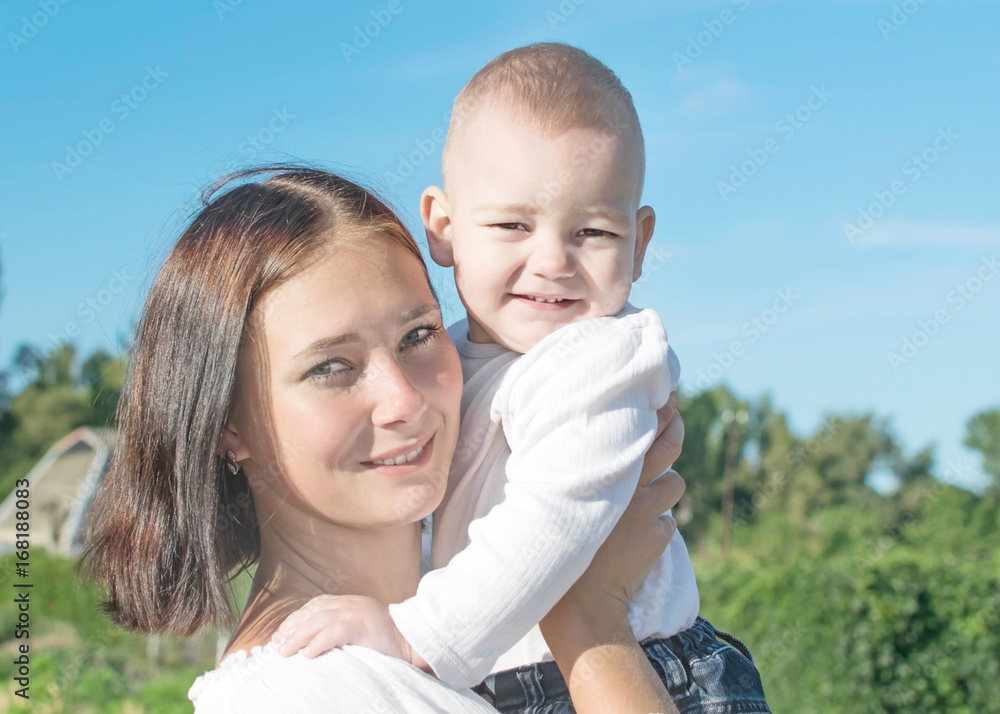 Portrait of a beautiful young mother holding a small baby son in village at sunny summer day Portrait of a beautiful young mother holding a small baby son in village at sunny summer day
