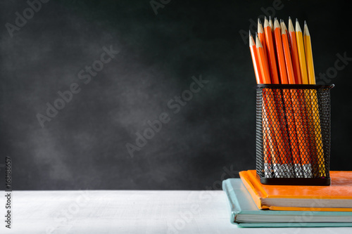 book and pencil on white table black board background with study and education