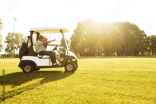 Two male golfers driving in a golf cart