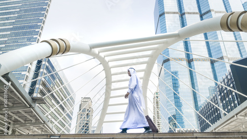 Photography arab traveler man carrying a suitcase and walk in city with the modern steel str