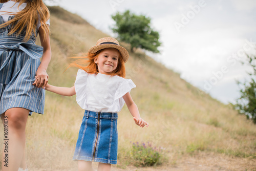mother and daughter walking on hill