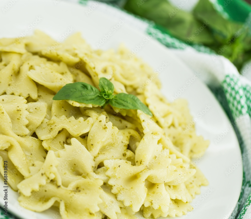 Farfalle pasta with pesto genovese (basil sauce) on white rustic wooden table. Italian cuisine Farfalle pasta with pesto genovese (basil sauce) on white rustic wooden table. Italian cuisine