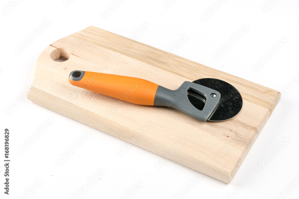 Black and orange round pizza knife on the cutting wooden board Black and orange round pizza knife on the cutting wooden board