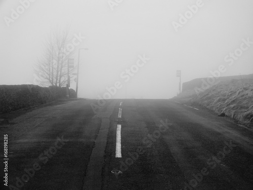 country road in heavy fog near to top of a hill with low visibility in winter © philopenshaw