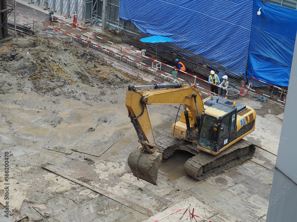 Fototapeta premium workers in construction area with crane truck and holding machine