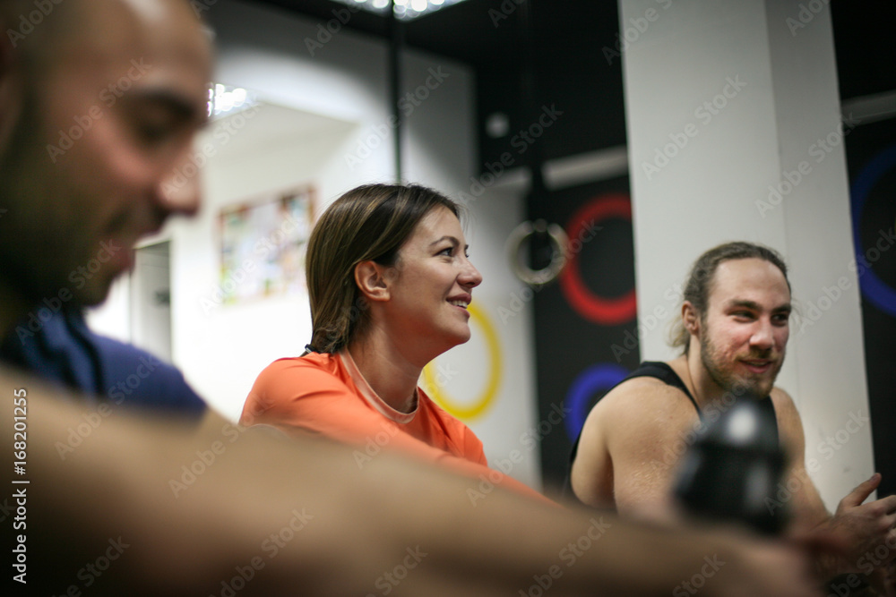 Three friends sitting on floor and having conversation after exercise. People workout in gym. Three friends sitting on floor and having conversation after exercise. People workout in gym.