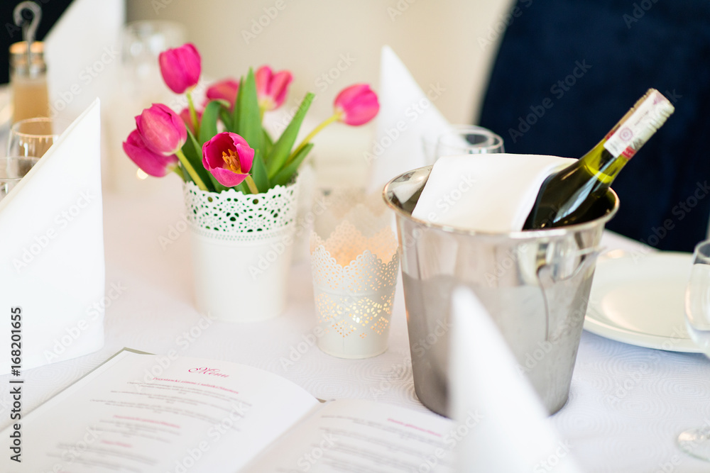 Stół w restauracji z wiaderkiem lodu i winem oraz karta dań menu i dekoracja z tulipanów  - obrazy, fototapety, plakaty 