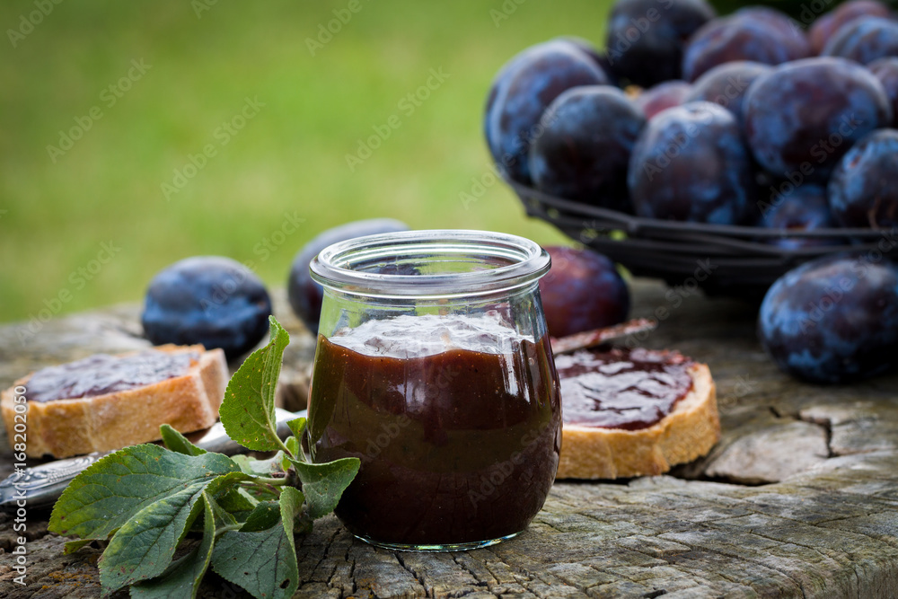 Sandwich with fresh plum jam lying on old wooden stump in garden. Sandwich with fresh plum jam lying on old wooden stump in garden.