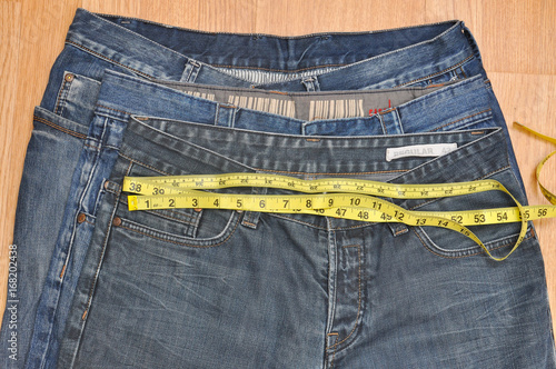 Measuring different size of jeans. Concept of losing weight, smaller size of jeans photo