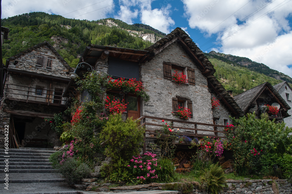 Sonogno small town in the swiss mountains. Street with old stone houses decorated with flowers.