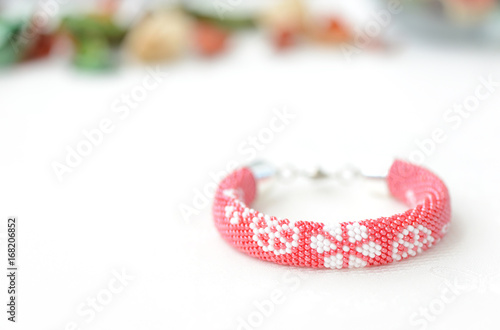 Red beaded bracelet with floral print on a textile background