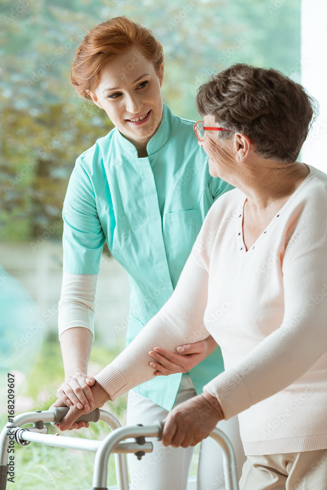 Fototapeta premium Nurse helping elder with walker
