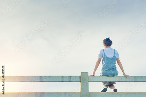 relax young woman sitting on fence in countryside.