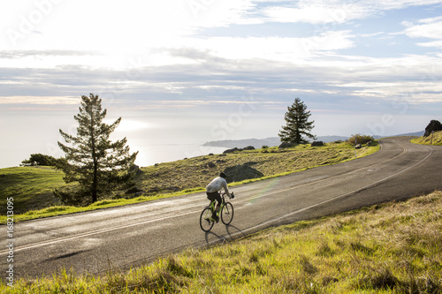 Caucasian man riding bicycle on road near ocean
