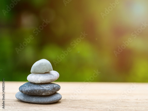 Four stones stacked placed on a wooden board. The backdrop is black on green.