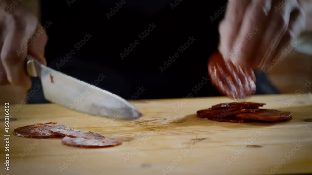 Cooking school. The chef cutting in half pieces of spicy dry sausage in the kitchen of a restaurant. 4K Cooking school. The chef cutting in half pieces of spicy dry sausage in the kitchen of a restaurant. 4K