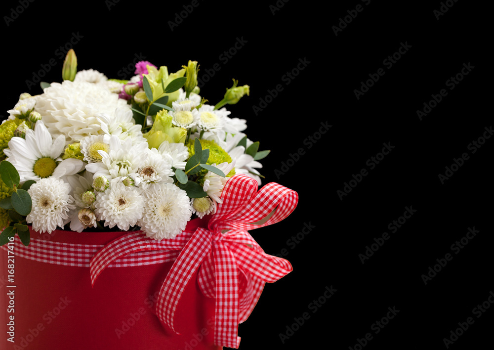 White daisies and chrysanthemums in a bouquet in a red box with a bow on a black background