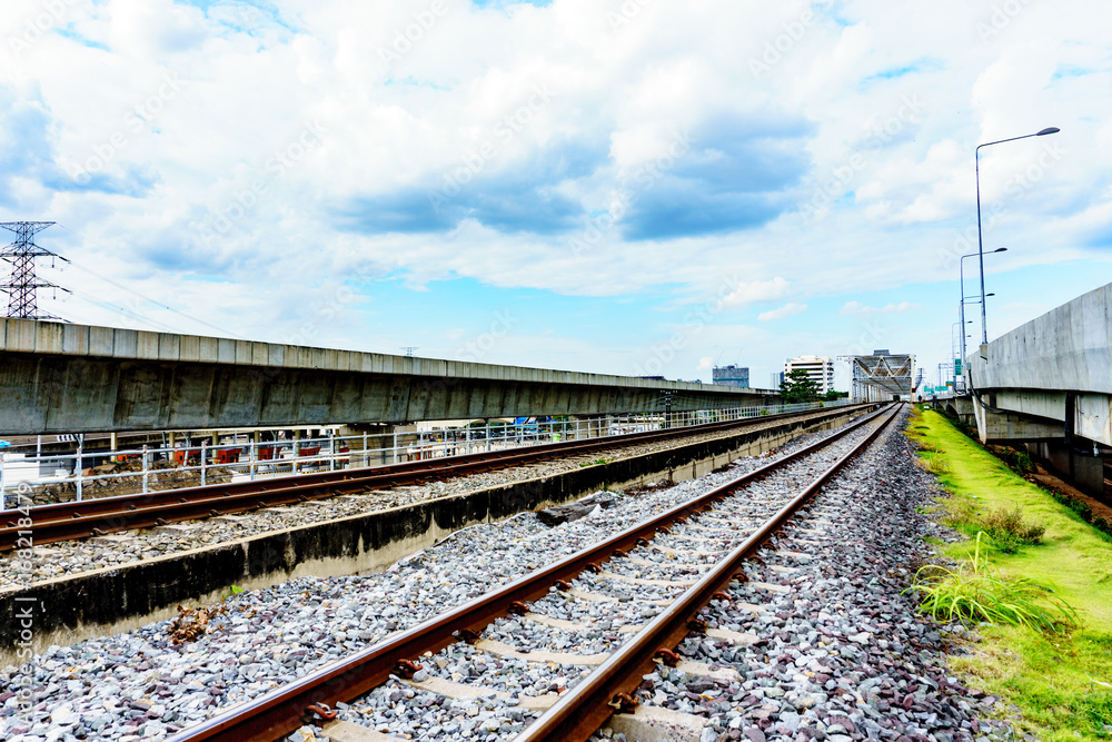 side view of railway track and crushes rock near the bridge with blue sky and cloudy background. milestone concept