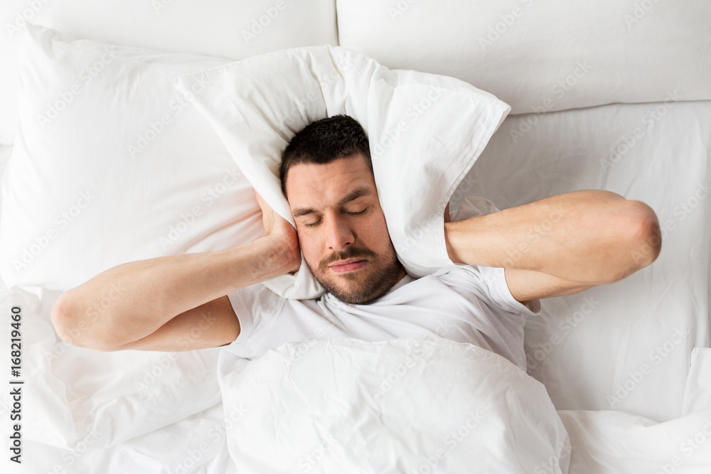 man in bed with pillow suffering from noise man in bed with pillow suffering from noise