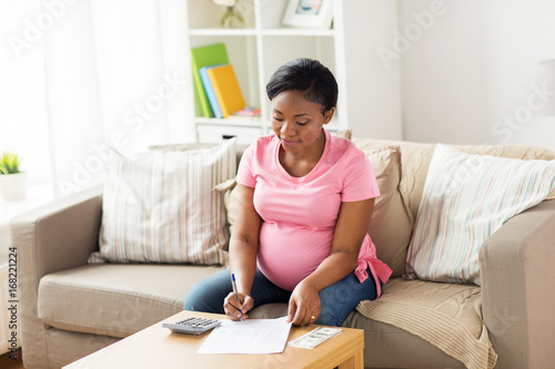 pregnant woman with bills and money at home