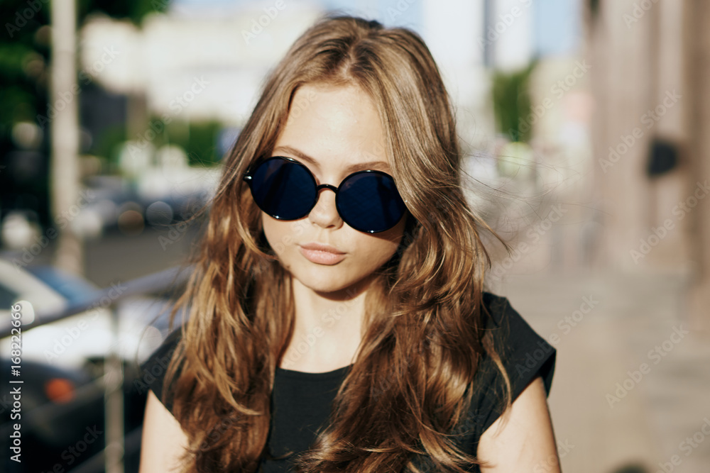 Young beautiful woman in sunglasses outside in the city, portrait