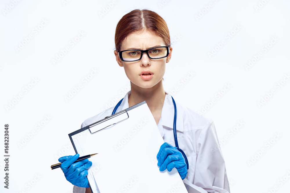 Woman on white isolated background in glasses and in medical robe holds documents Woman on white isolated background in glasses and in medical robe holds documents