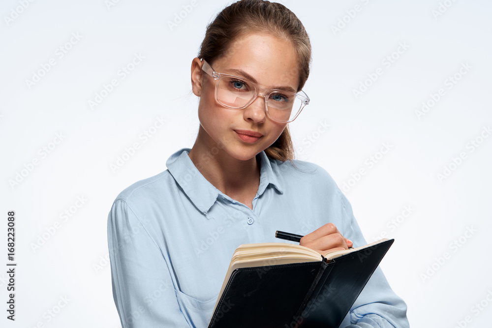 Young beautiful woman in glasses on white isolated background writes in notebook, portrait Young beautiful woman in glasses on white isolated background writes in notebook, portrait