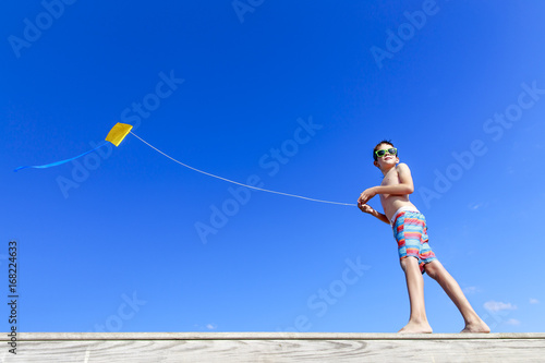 Boy with flying kite.  boy on the beach playing with a kite on the background of blue sky. Copy space for your text