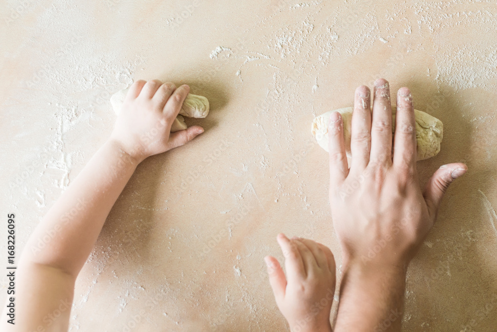 Fototapeta premium Children's and dad's hands makes raw dough
